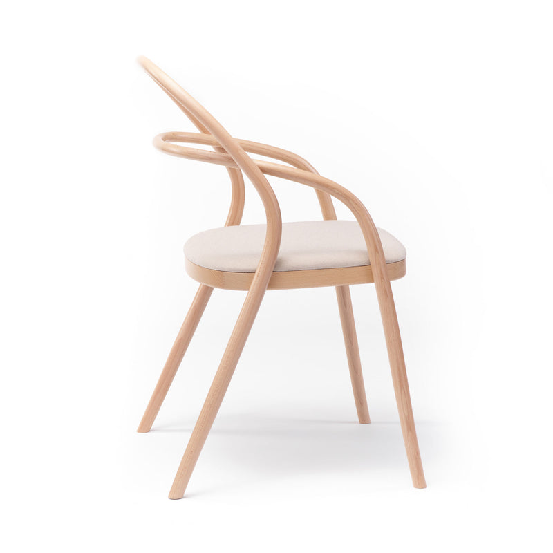 Chair 002 - Upholstered by TON is a modern minimalist chair featuring a light wood frame, cream-colored cushioned seat, and a distinctive curved backrest. Its design echoes the No. 14 redesign by TONDesigner, showcased against a plain white background.