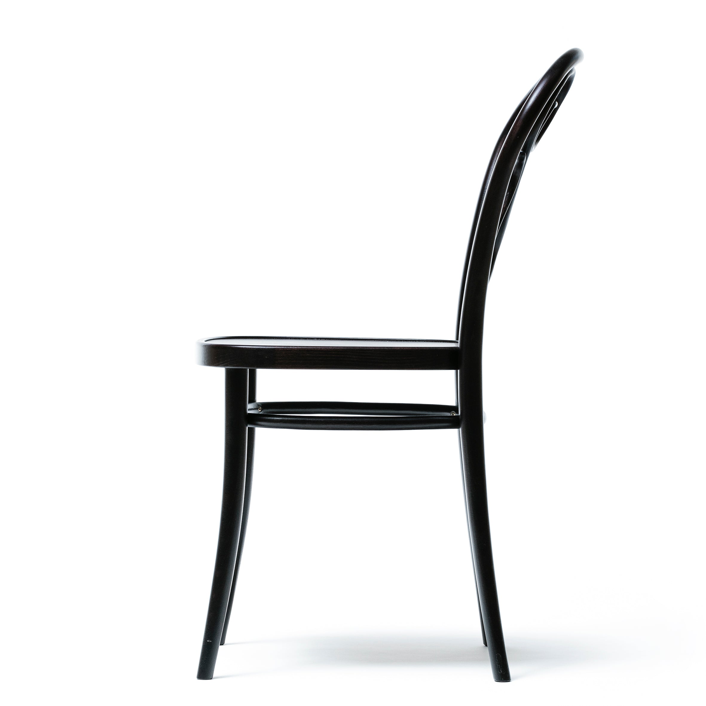Side view of Chair 04 - Cane by TON, a sleek black wooden dining chair with a minimalist design, featuring a curved backrest and four slender legs with subtle bent details, set against a plain white background.