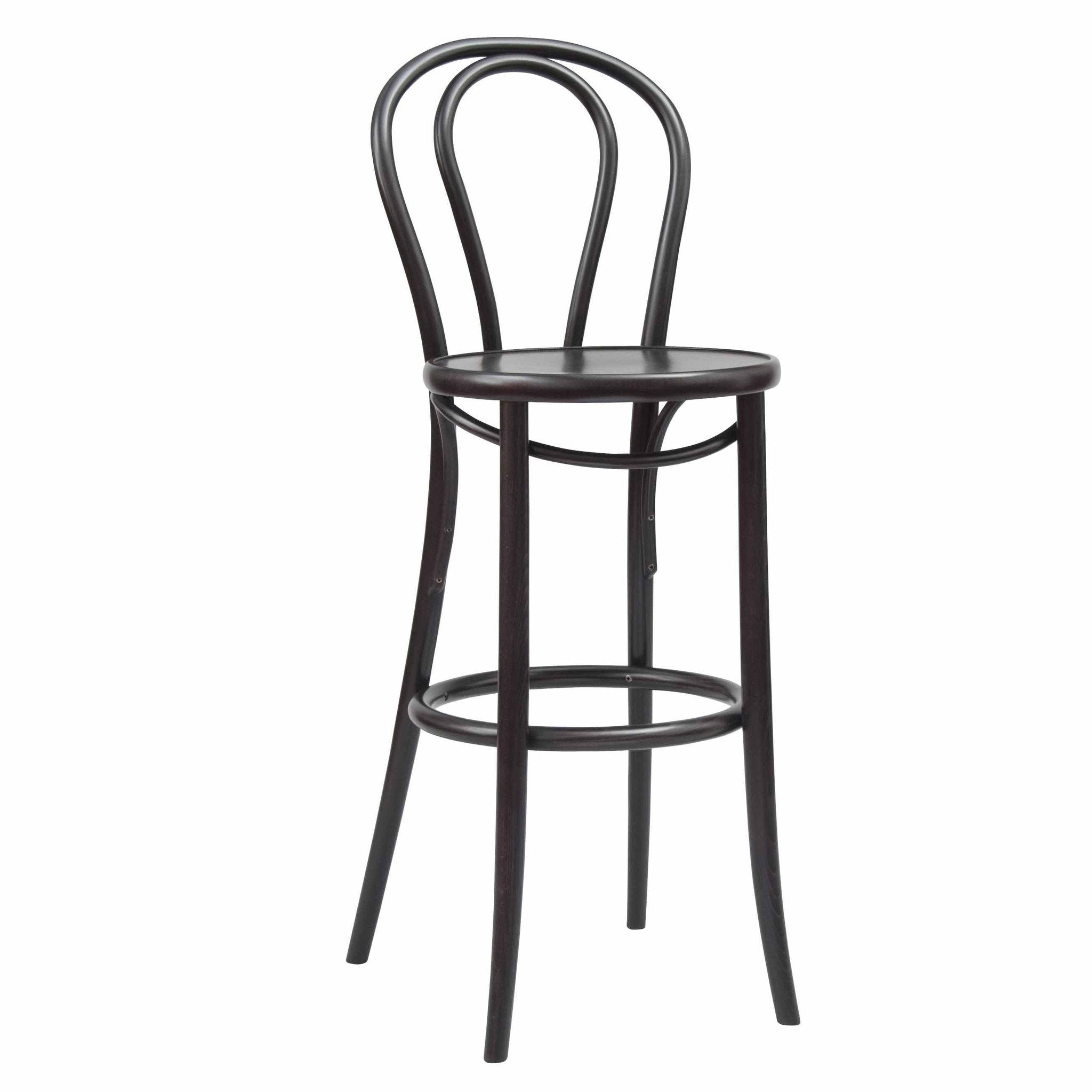 The TON Barstool 18 is a tall, elegant piece with a curved backrest and circular seat made of smooth plywood. It features four slender legs and a round footrest, blending classic design with refined upholstery accents.