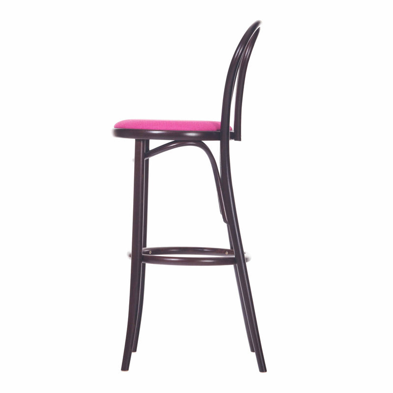 The Barstool 18 by TON is a side-view, tall, dark wooden barstool featuring a pink upholstered seat. It has a curved backrest with vertical supports and includes a footrest on its legs, offering a simple, modern plywood design.