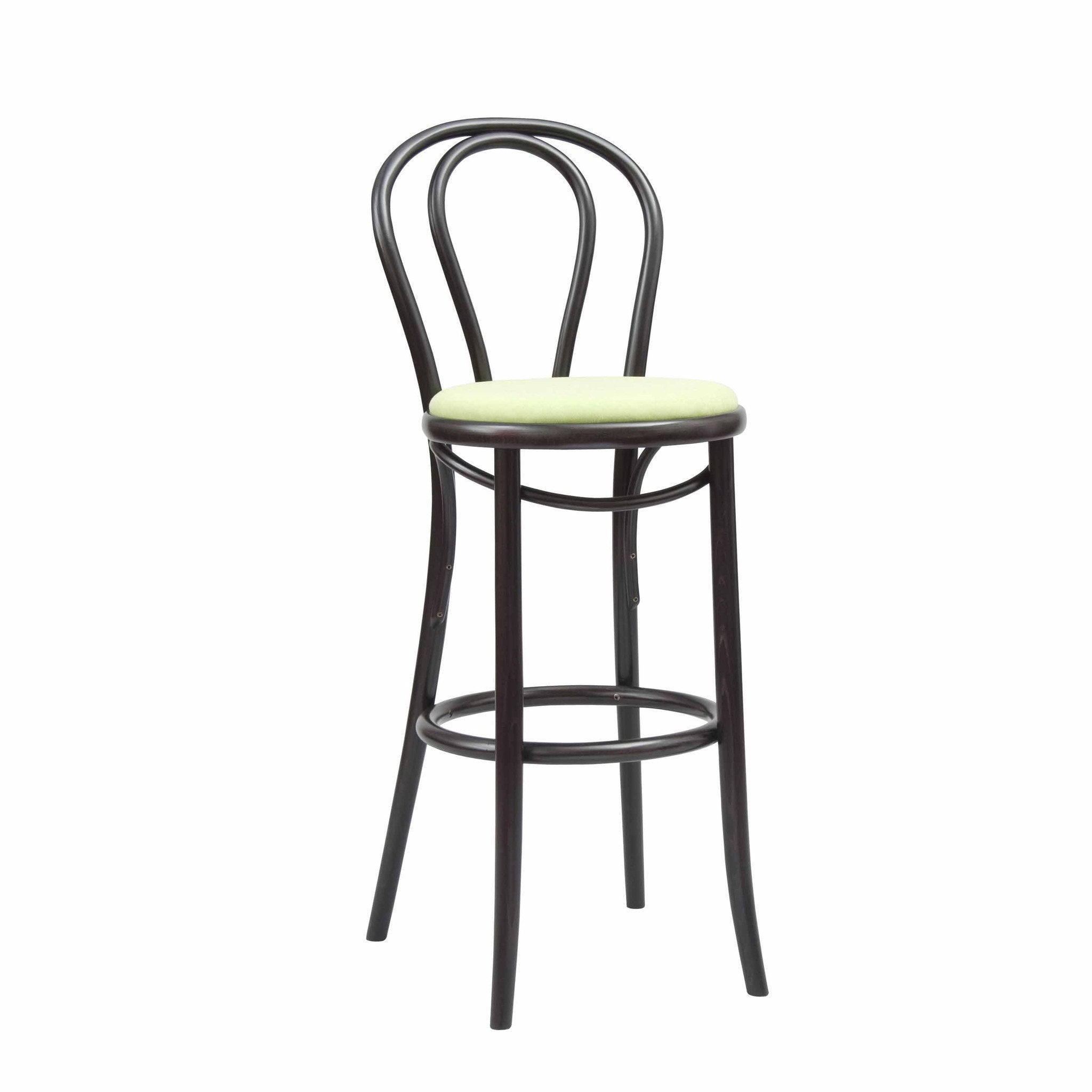 The TON Barstool 18 is a tall, dark wooden barstool featuring a curved backrest, light green cushioned seat with expert upholstery for comfort, circular footrest, and four slender legs; it seamlessly blends function and style.