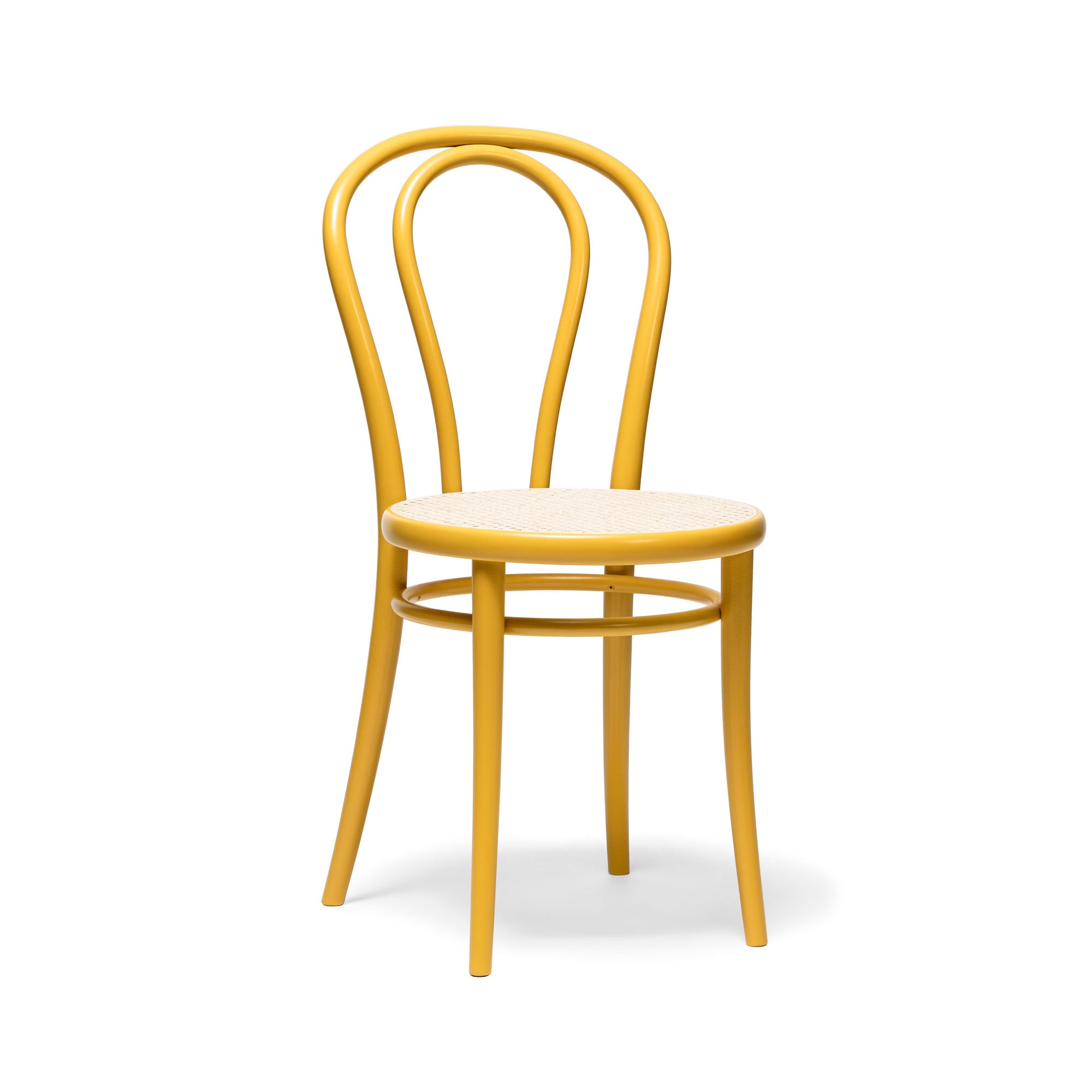 The Chair 18 - Cane by TON is a classic bistro-style dining chair in yellow with a rounded backrest and woven seat, crafted from beech wood. It features a smooth, curved frame and four straight legs.