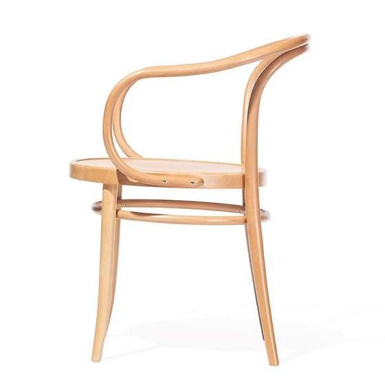 The Armchair 30 by TON is a light wooden chair with an open, curved backrest and armrest. It features a minimalist design with a rounded seat and slender legs, offering a modern look suitable for versatile use.