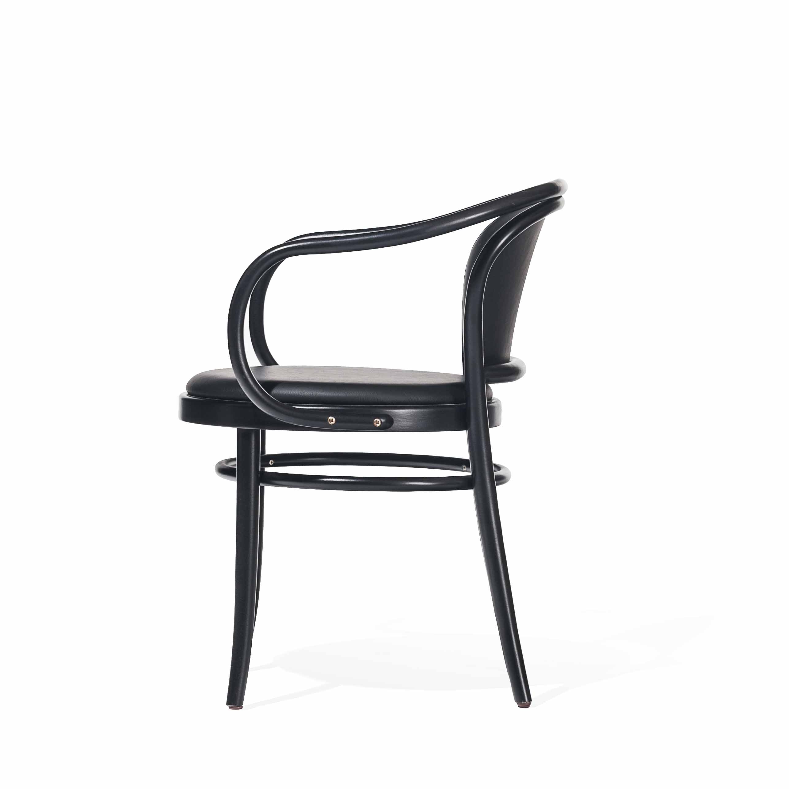 The Armchair 33 by TON is a sleek, modern black chair with a curved backrest and armrest design. It features a round cushioned seat and four slender legs, shown in a side view against a white background.