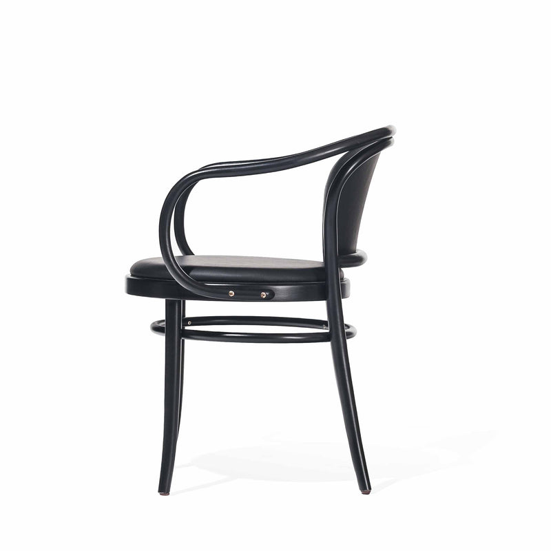 The Armchair 33 by TON is a sleek, modern black chair with a curved backrest and armrest design. It features a round cushioned seat and four slender legs, shown in a side view against a white background.