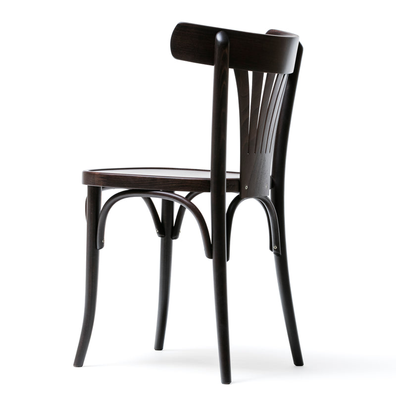 The Chair 56 by TON is displayed against a white background. Its a black wooden dining chair featuring a curved backrest with vertical slats and slender legs, showcasing a simple yet elegant design.