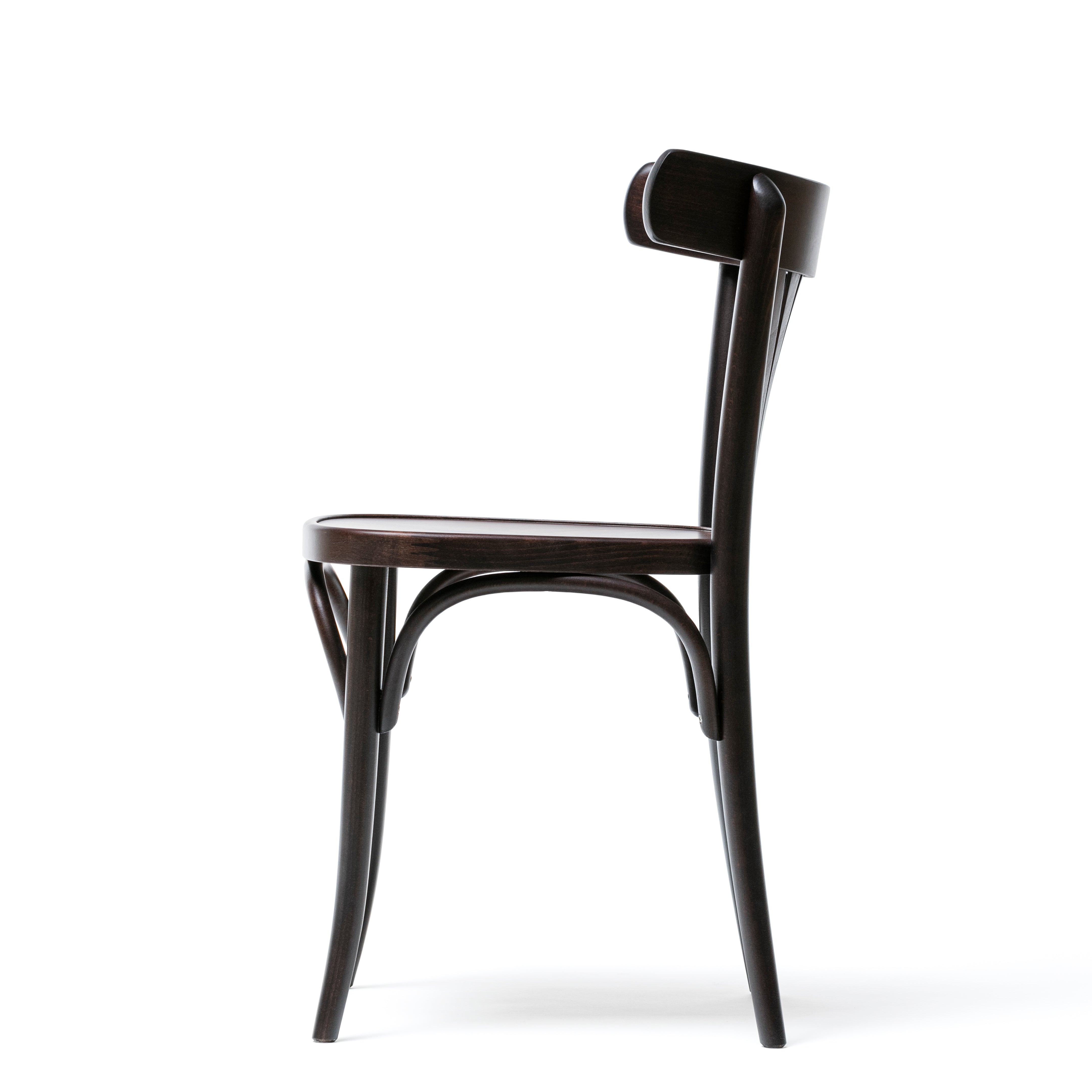 The side view of the sleek, dark Chair 56 by TON highlights its design with a curved backrest and legs. This minimalist piece offers simple elegance, enhanced by a plywood fan backrest.