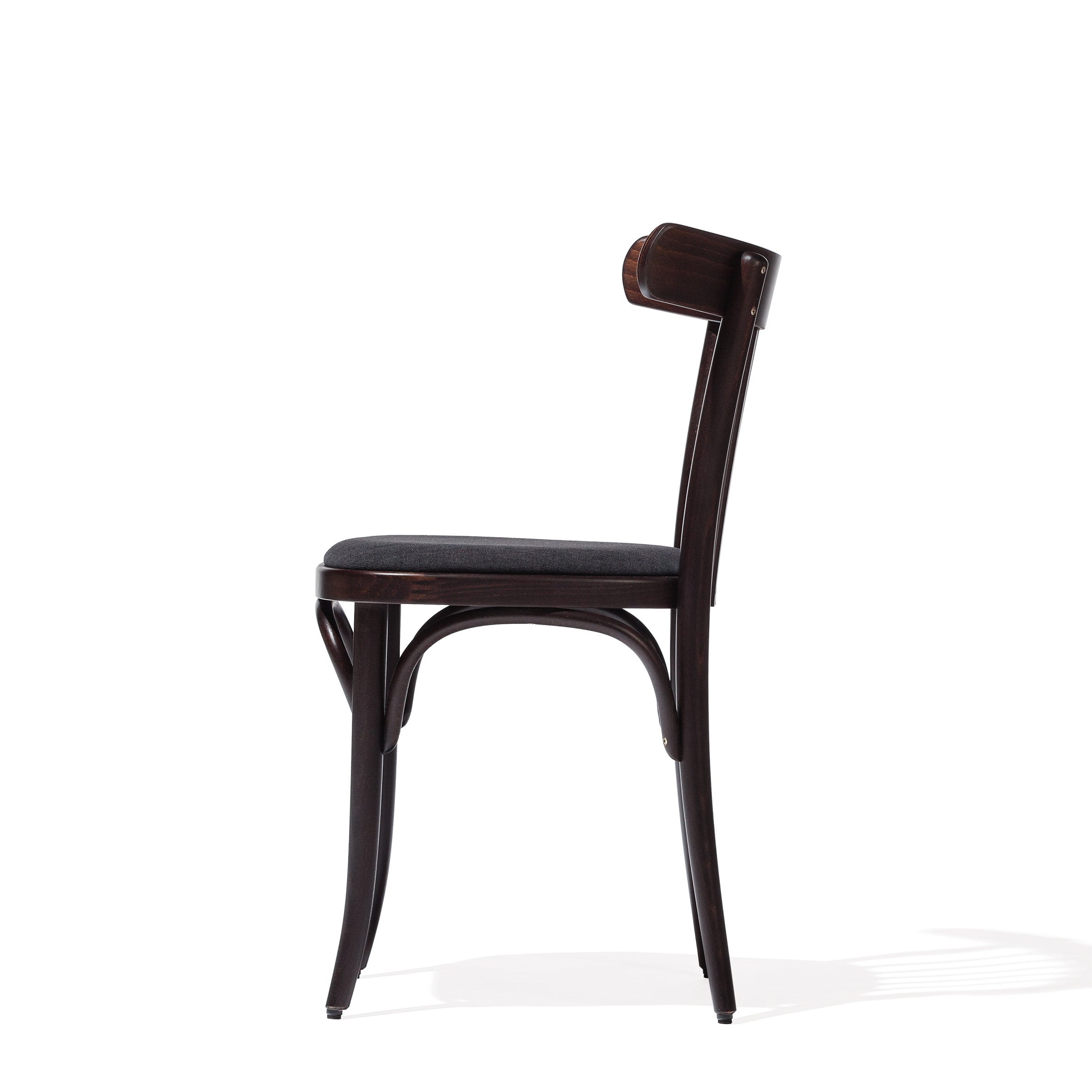 A side view of Chair 763 by TON showcases its curved backrest and cushioned seat in a dark finish. Made from beech, the slightly curved legs cast a shadow on the white background, ideal for modern interiors.