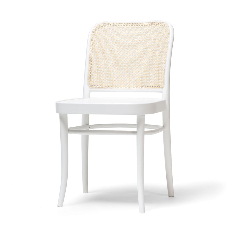 The Chair 811 by TON features a white cane backrest in an Art Nouveau style. Its smooth, rounded edges and flat seat sit on gracefully curved legs, embodying a classic minimalist design akin to a Josef Hoffmann chair.