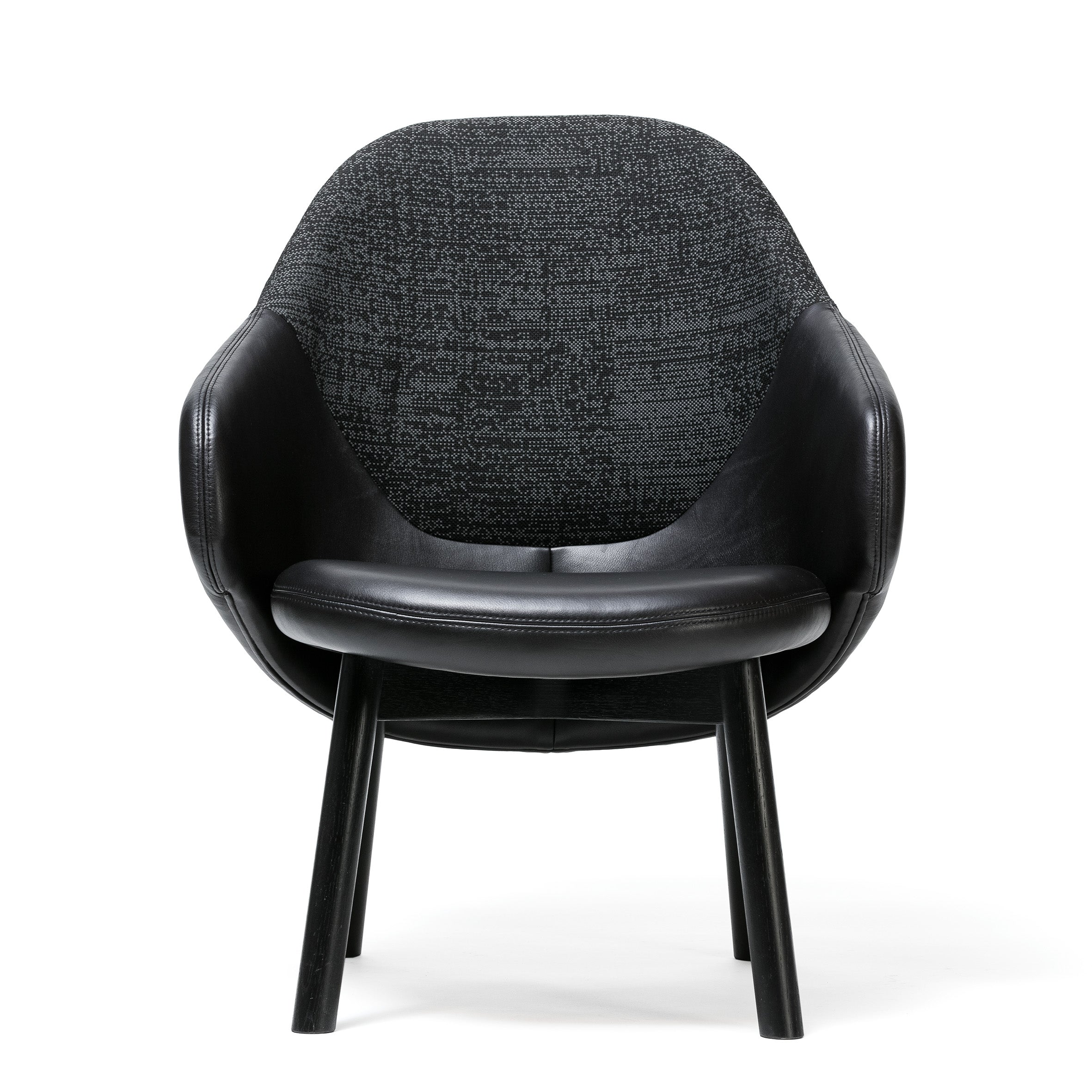 The Lounge Armchair Albu by TON is a modern black chair featuring a textured fabric backrest, leather-like arm and seat upholstery, and four black wooden legs. It offers perfect ergonomics with its minimalist design, displayed against a white background.