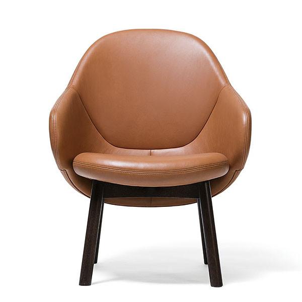 The Lounge Armchair Albu by TON is a modern brown leather chair featuring a rounded, smooth backrest, dark wooden legs, and perfect front-view ergonomics.
