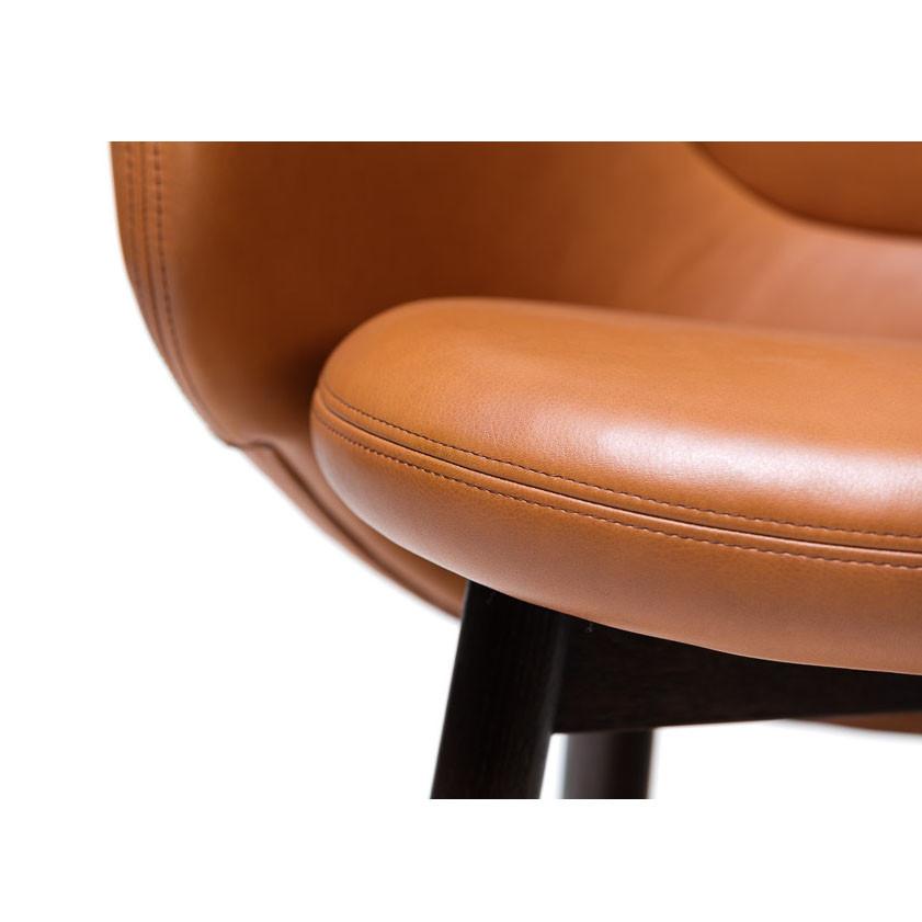 The Lounge Armchair Albu by TON features smooth, tan leather upholstery with visible stitching and dark wood legs that contrast beautifully with the light seat. This modern design combines sleek aesthetics and perfect ergonomics for ultimate comfort.