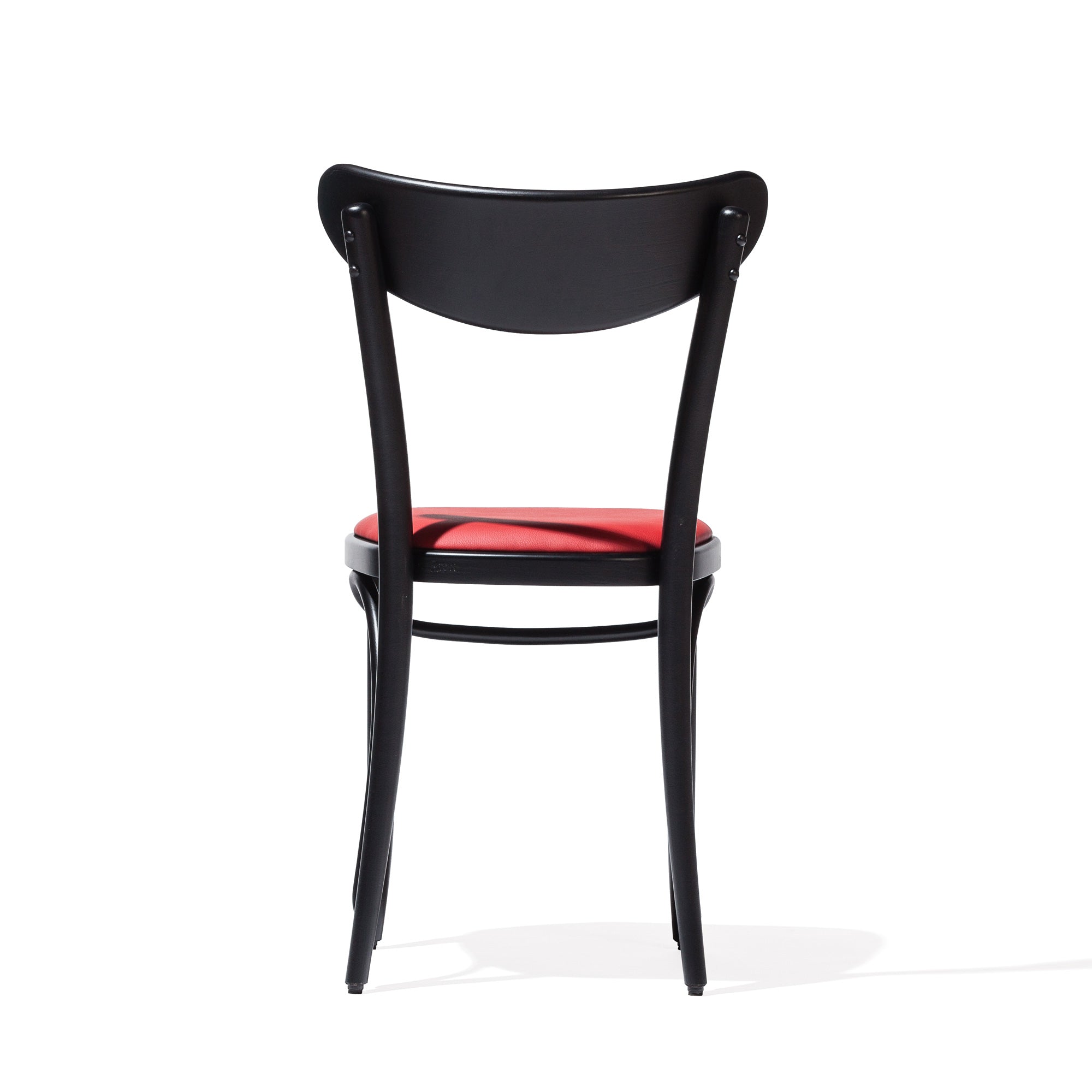 The Chair Banana by TON is a minimalistic black bentwood chair with a red upholstered seat, showcased from the back against a plain white backdrop. It boasts a smooth, curved plywood backrest and elegant design.
