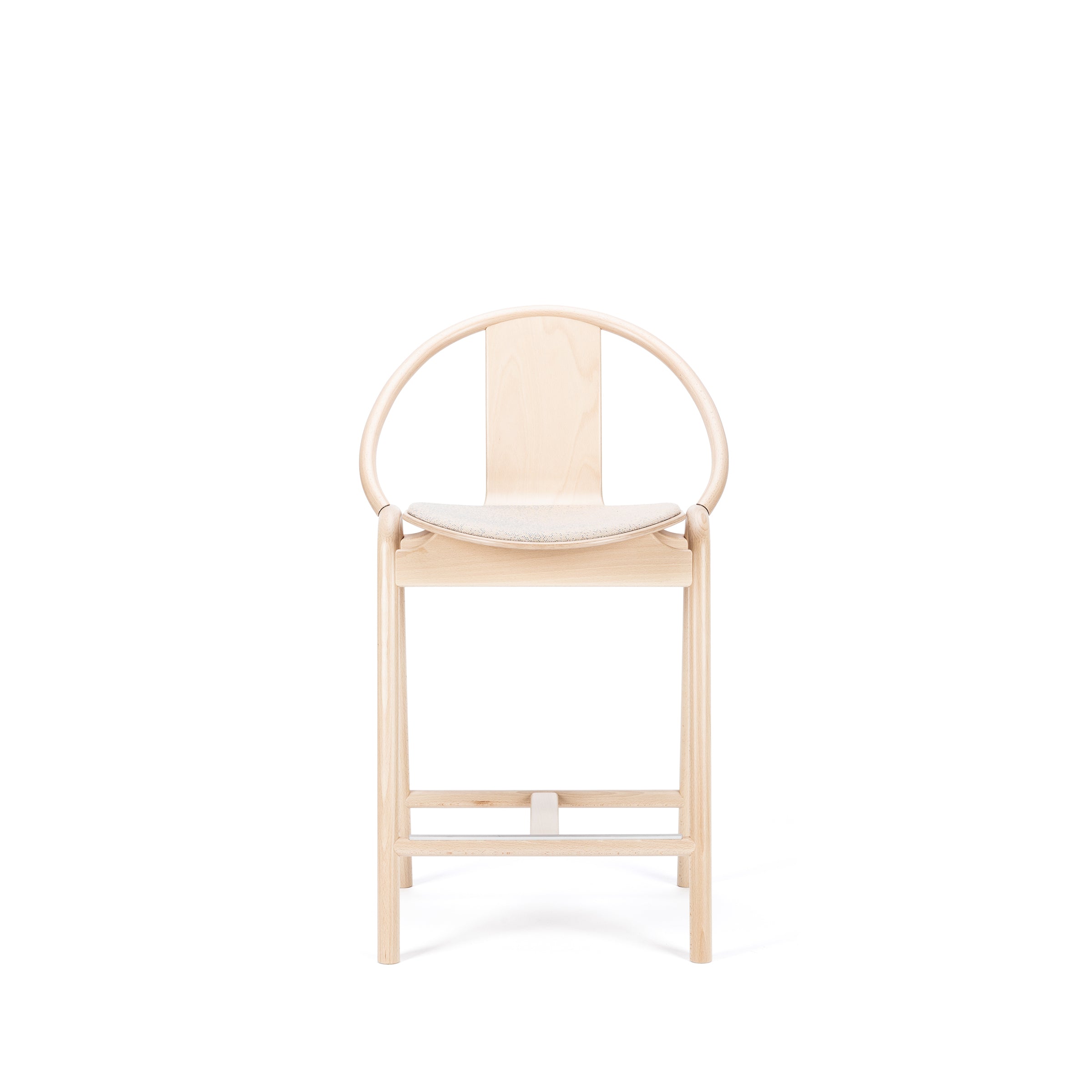 The Barstool Again Upholstered by TON is a minimalist wooden chair with a curved backrest and cushioned seat against a white backdrop. Its light wood finish and sleek, modern design capture the elegance of handcrafted furniture.