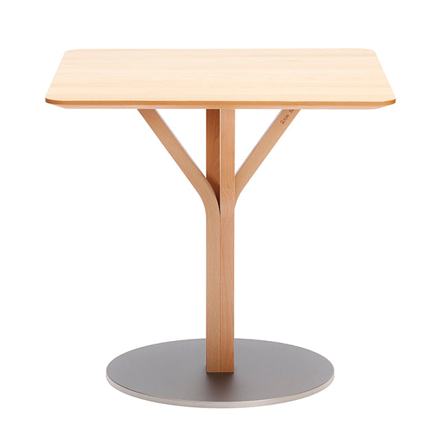 The Bloom Bistro Table Square by TON is a small, square wooden table with a light wood finish. It has a Y-shaped central support on a round metal base, combining simplicity and elegance, perfect for those seeking stylish solid wood tables.