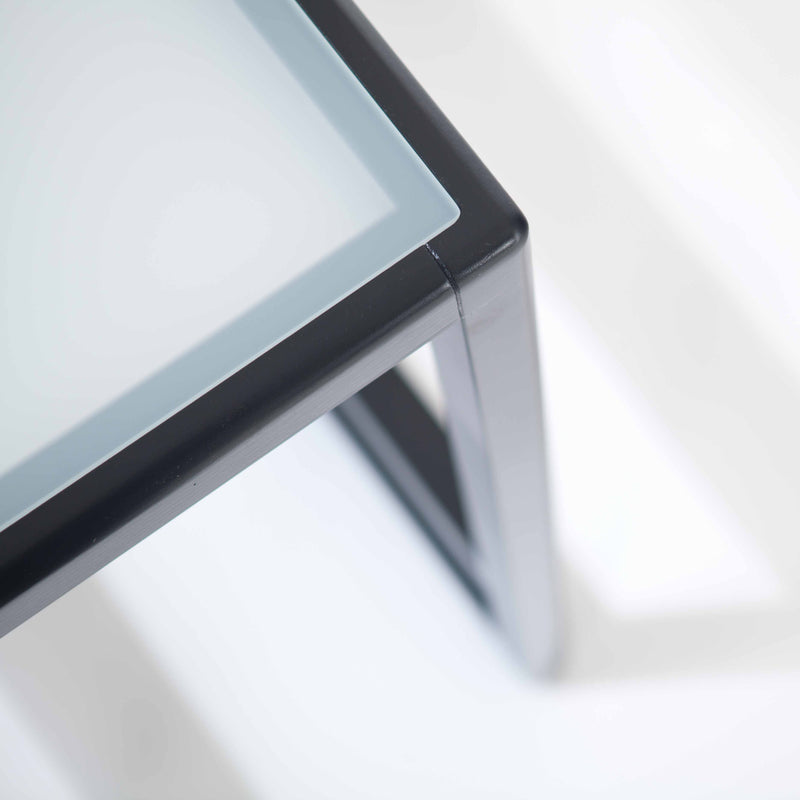 Close-up view of a Side Table Casablanca by TON, showcasing a frosted glass top with sleek black metal legs, elegantly set against a light background.