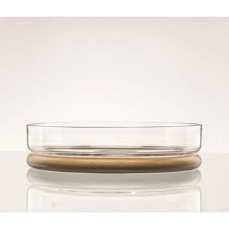 The Hoop Bowl by TON is a clear, round dish made of Czech crystal glass on a flat wooden base, showcasing bent wood craftsmanship with minimalist design: a smooth top and light brown bottom reflecting refined aesthetics.