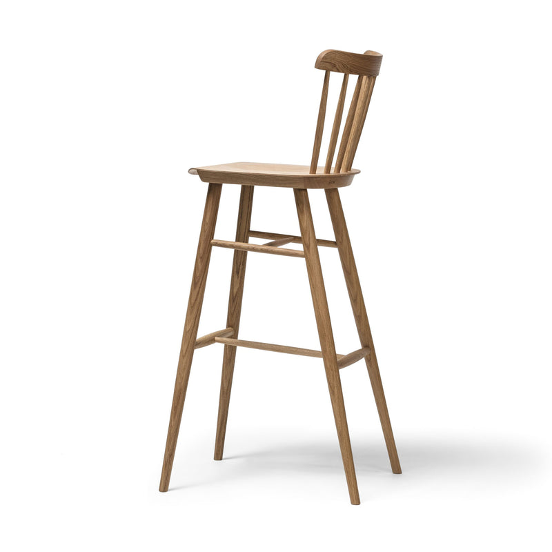 The Barstool Ironica by TON is crafted from beech and oak, featuring a high backrest, slim legs, and a smooth wooden seat. Hand-finished dowels add elegance, complemented by a footrest bar against a plain white background.
