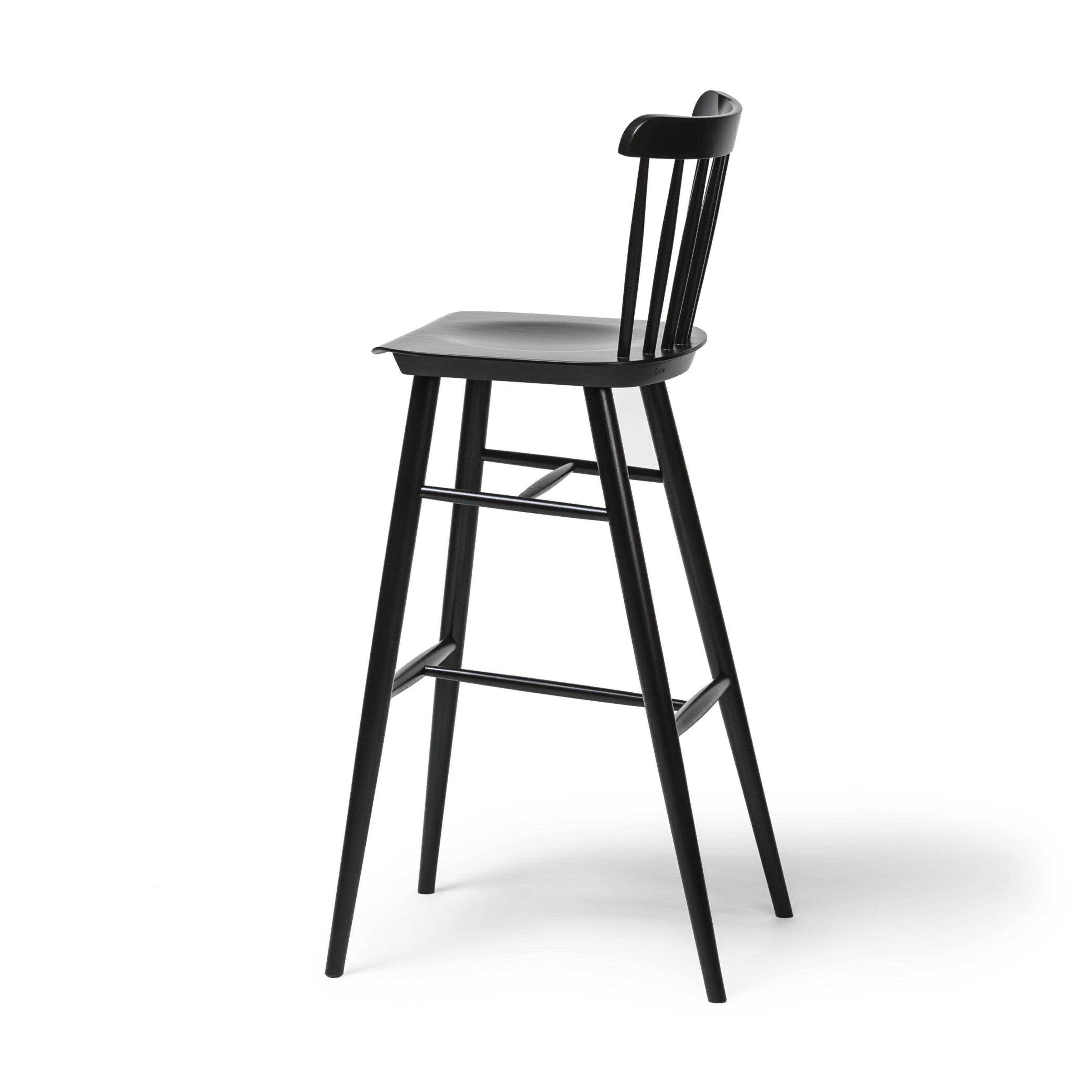 Introducing the Barstool Ironica by TON, crafted from elegant beech and oak. This sleek black wooden stool features a tall backrest, four slightly angled legs with hand-finished dowels, and a footrest connecting the front two legs, all set against a plain white background.
