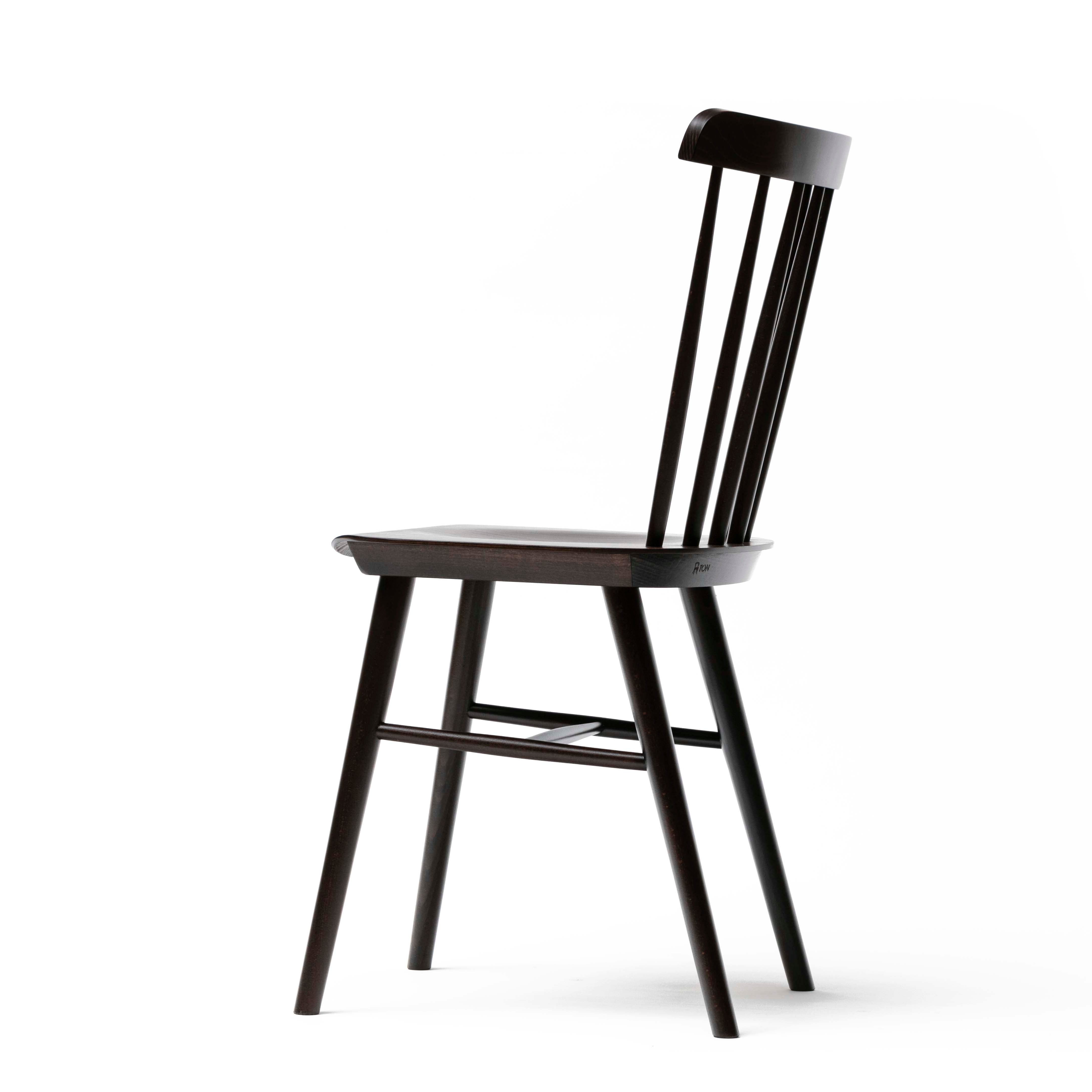 The side view of the Chair Ironica by TON showcases a modern dark wooden design with retro flair, featuring a high backrest with vertical slats and four slender legs. Minimalist lines and a sophisticated silhouette highlight its elegance.