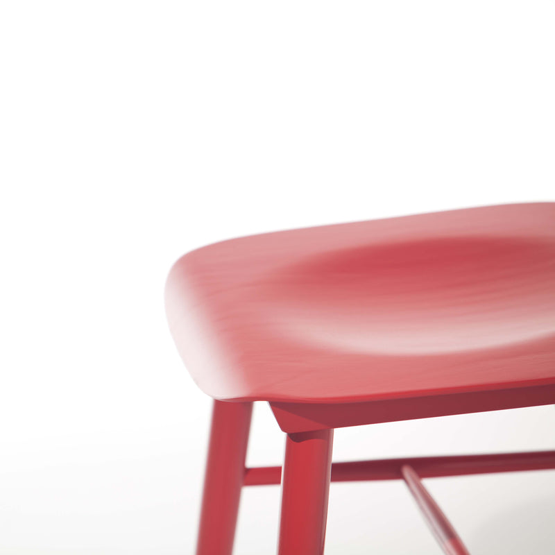 A partial view of the modern, red Chair Ironica by TON against a white background. The image highlights its sleek, minimalist design with a retro touch, focusing on the curved seat and part of the legs.