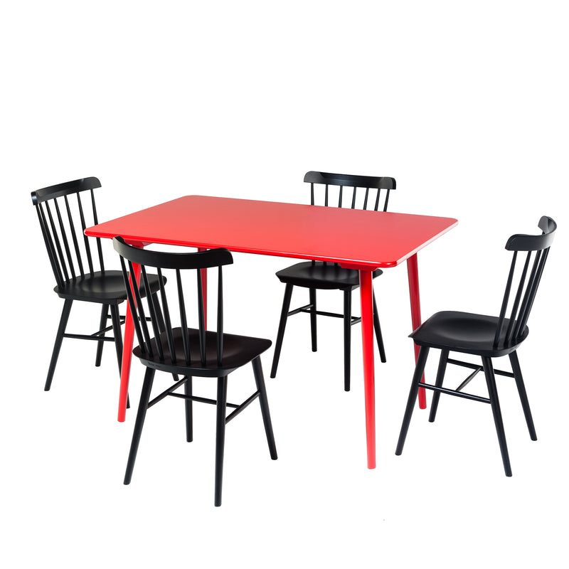 The Table Ironica by TON is a bright red rectangular table made from solid beech, paired with four black spindle-backed wooden chairs. This setup highlights the sleek, retro contrast of red and black against a plain white backdrop, creating a simple yet modern ambiance.