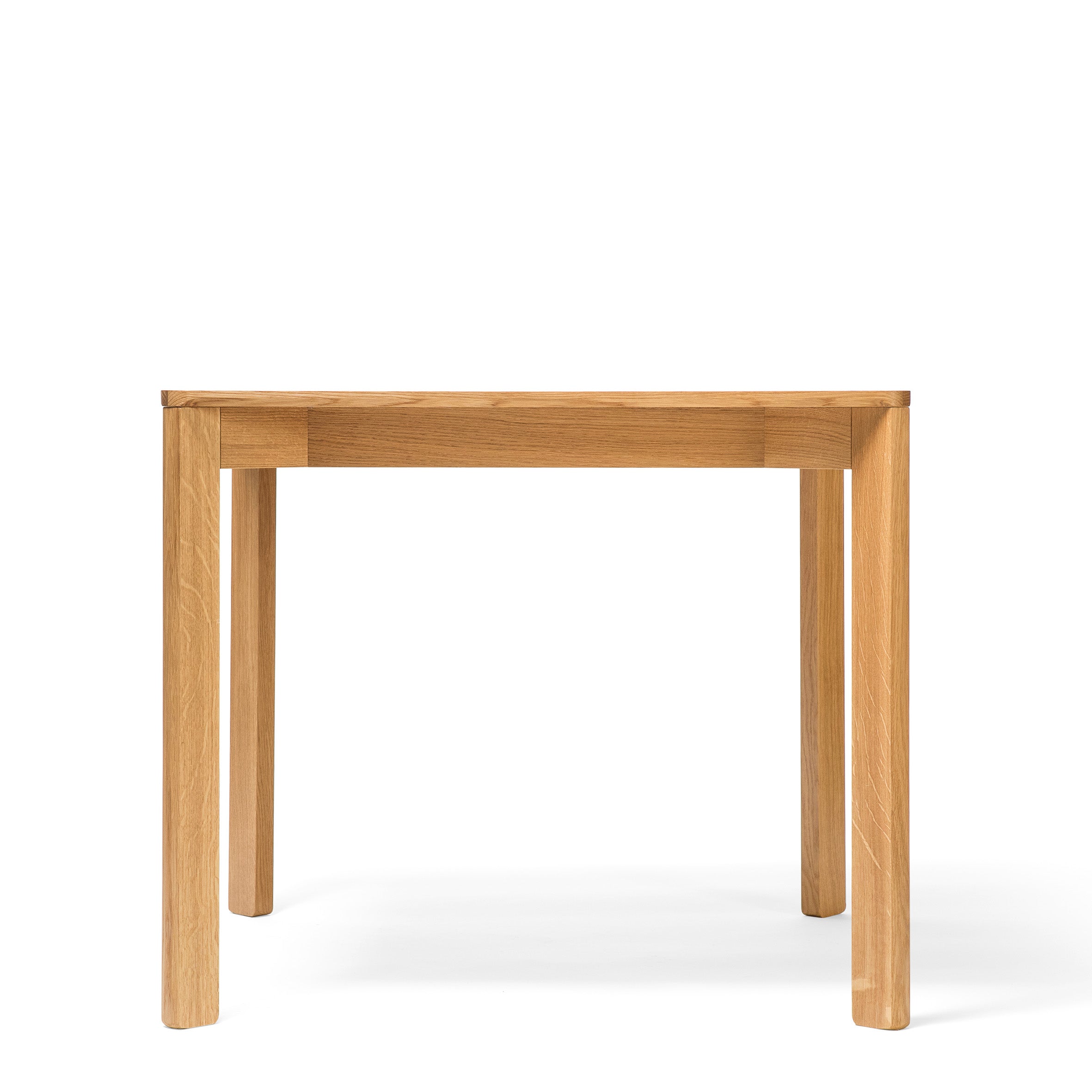 The Lasu table by TON is a rectangular solid wood piece boasting four sturdy legs and a light wood finish, ideal for a conference room with a plain white backdrop.