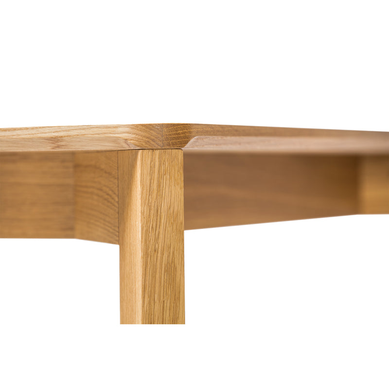 Close-up of a Lasu table corner, by TON, showcasing its natural wood grain and smooth finish. The rectangular top and sturdy legs highlight its minimalist design, while the warm polished wood creates an inviting atmosphere.