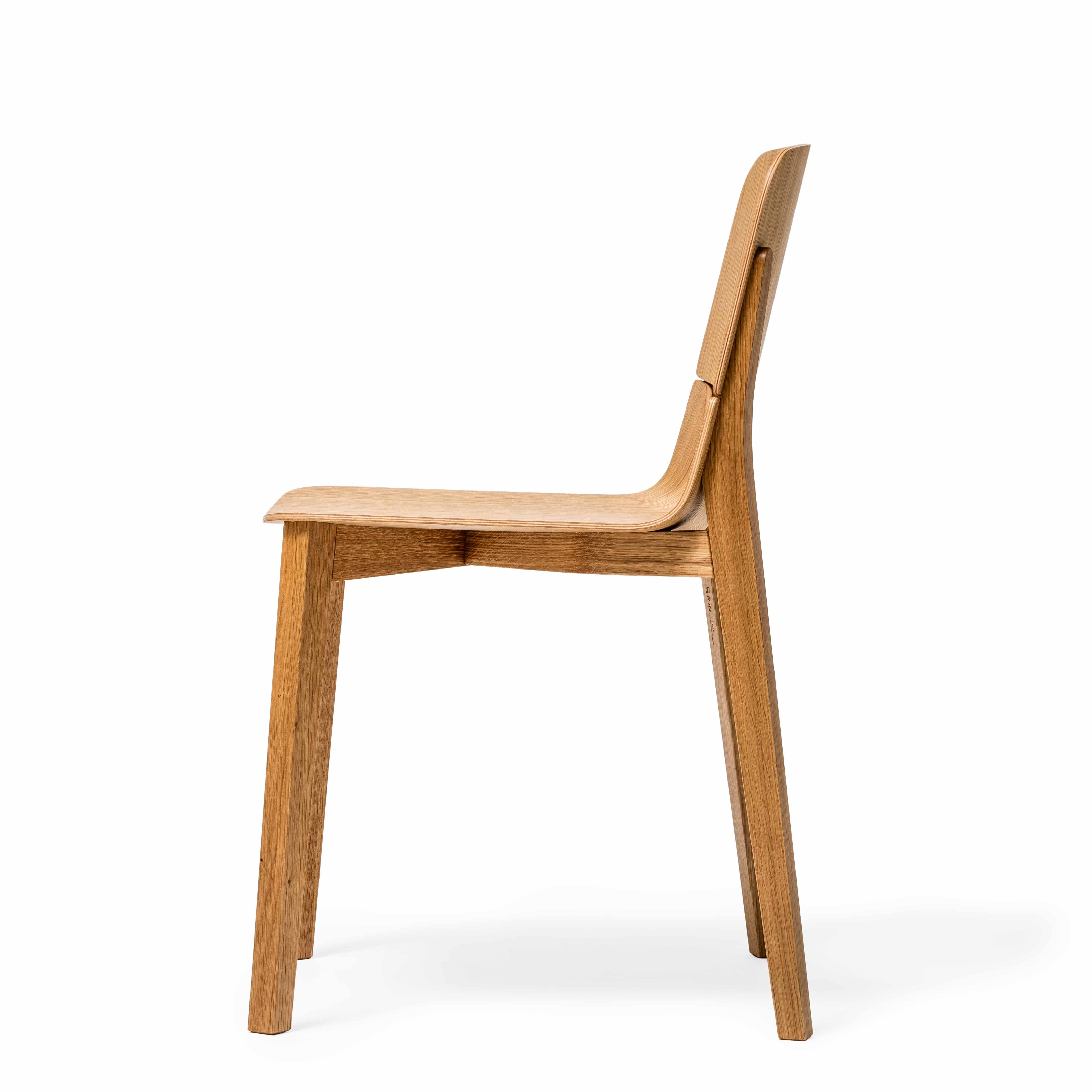 The Chair Leaf - Upholstered by TON is shown from the side, showcasing a minimalist design with an ergonomically curved backrest, straight legs, and a natural wood finish. It offers a modern aesthetic thats ideal for enhancing any dining area.