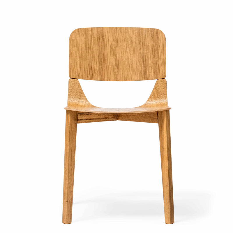 The Chair Leaf - Upholstered by TON features an elegantly curved backrest, straight legs, and a minimalist design. It’s part of the Leaf collection with a natural wood grain pattern. Displayed on a plain white background, it offers ergonomic comfort and striking visual appeal.