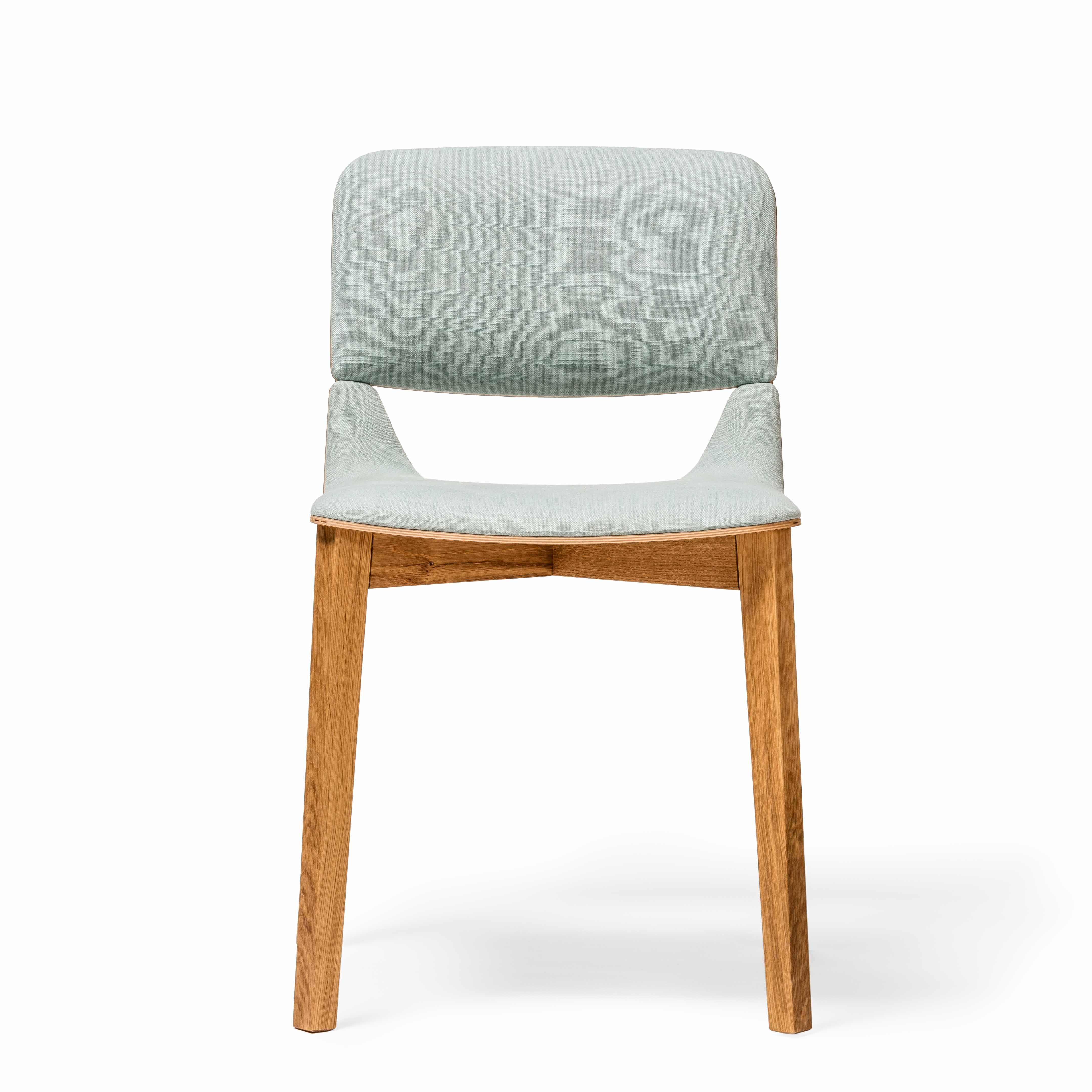 The TON Chair Leaf - Upholstered is a modern dining chair with ergonomic features, light gray cushioned seat and backrest, wooden legs, a slight seat curve, rectangular backrest, and straight polished legs for a clean look.