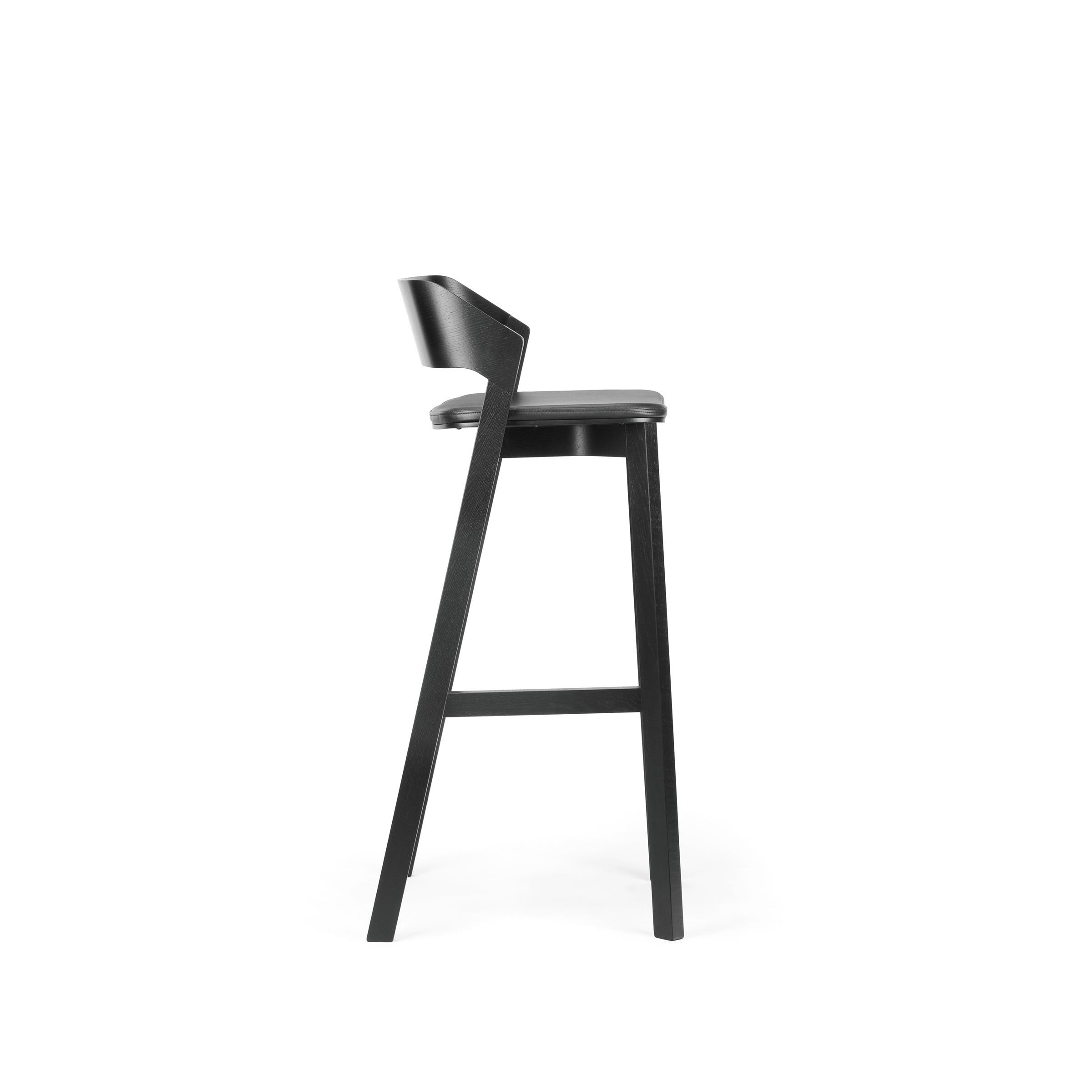 Side view of the Barstool Merano by TON, showcasing a modern black wooden design with a curved backrest and cushioned seat. It features sleek, angled legs and a footrest against a white background.