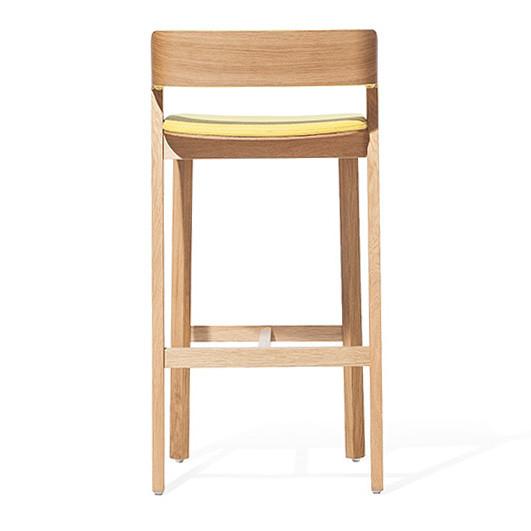 The Barstool Merano by TON features a modern design with a light solid wood finish, low backrest, and straight legs connected by a support bar. It includes an upholstered yellow cushioned seat for enhanced comfort.