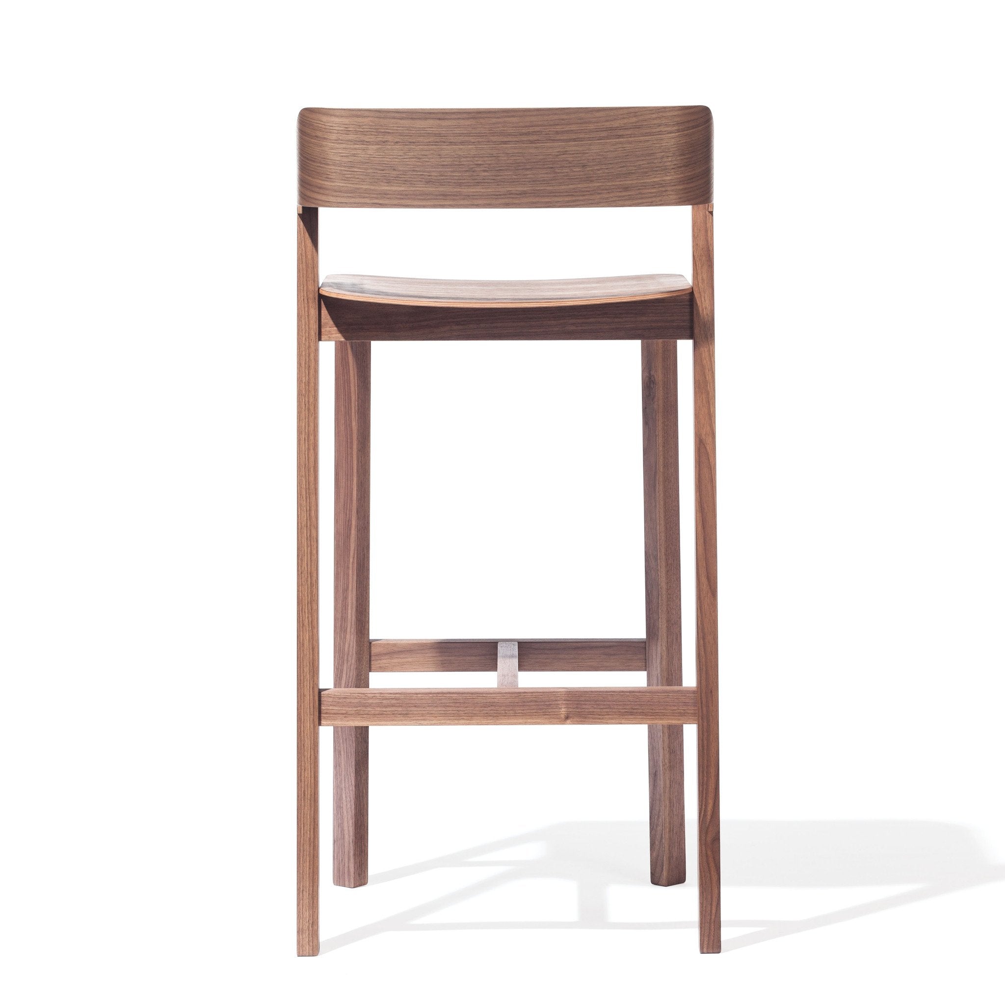 Discover the Barstool Merano - Sale by TON, crafted from solid wood and bent plywood. This minimalist wooden stool features a gracefully curved backrest, simple lines, and four legs with horizontal supports, showcasing elegance from every angle.
