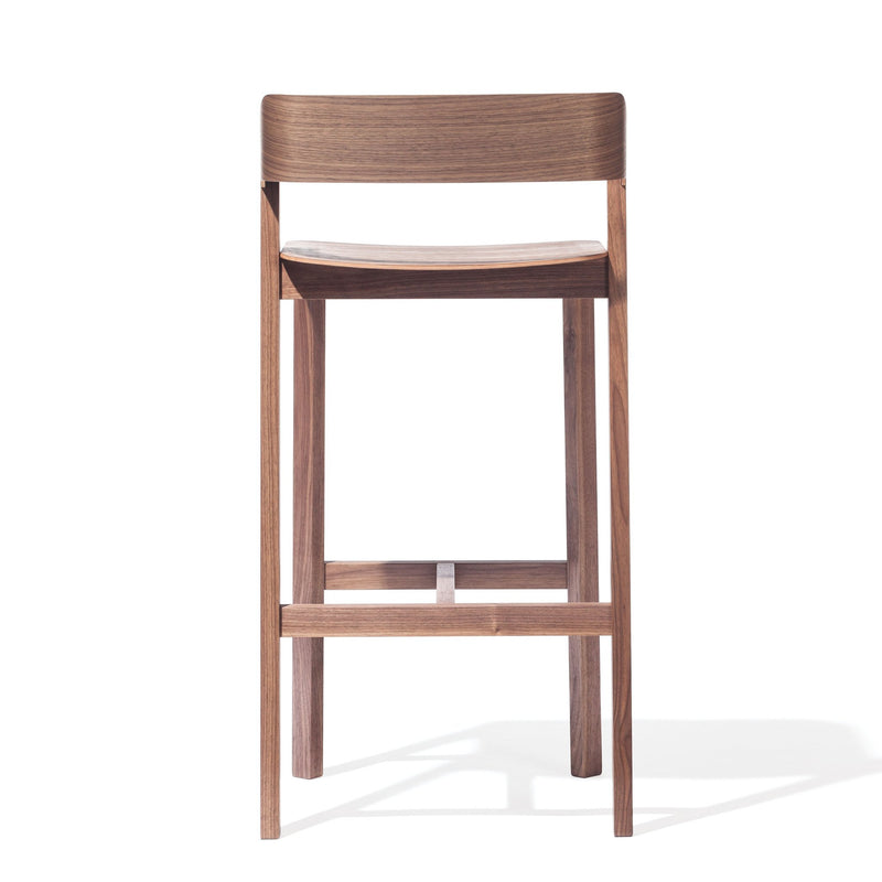 Discover the Barstool Merano - Sale by TON, crafted from solid wood and bent plywood. This minimalist wooden stool features a gracefully curved backrest, simple lines, and four legs with horizontal supports, showcasing elegance from every angle.