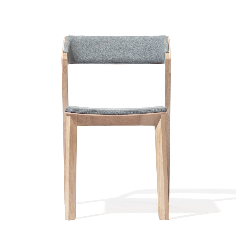 The Chair Merano Upholstered by TON boasts a minimalist design with solid wood construction, a light gray cushioned backrest and seat, straight legs for a modern look, and is set against a plain white background to highlight its sleek silhouette.