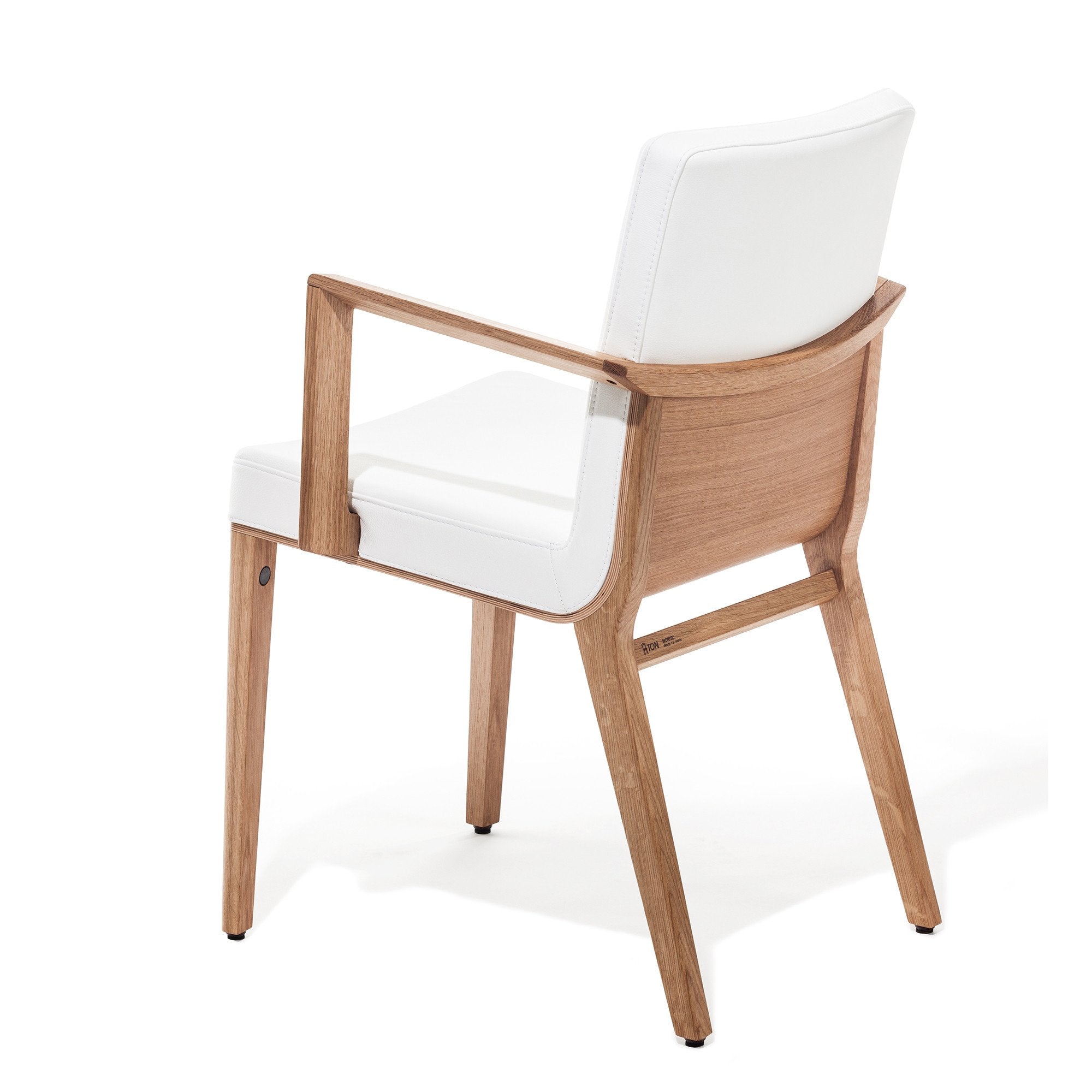 The Armchair Moritz by TON, designed by Kai Stania, features a white cushioned backrest and seat. Its clean lines, open back, and light-colored wooden frame underscore its minimalist, contemporary elegance—a true premium product.