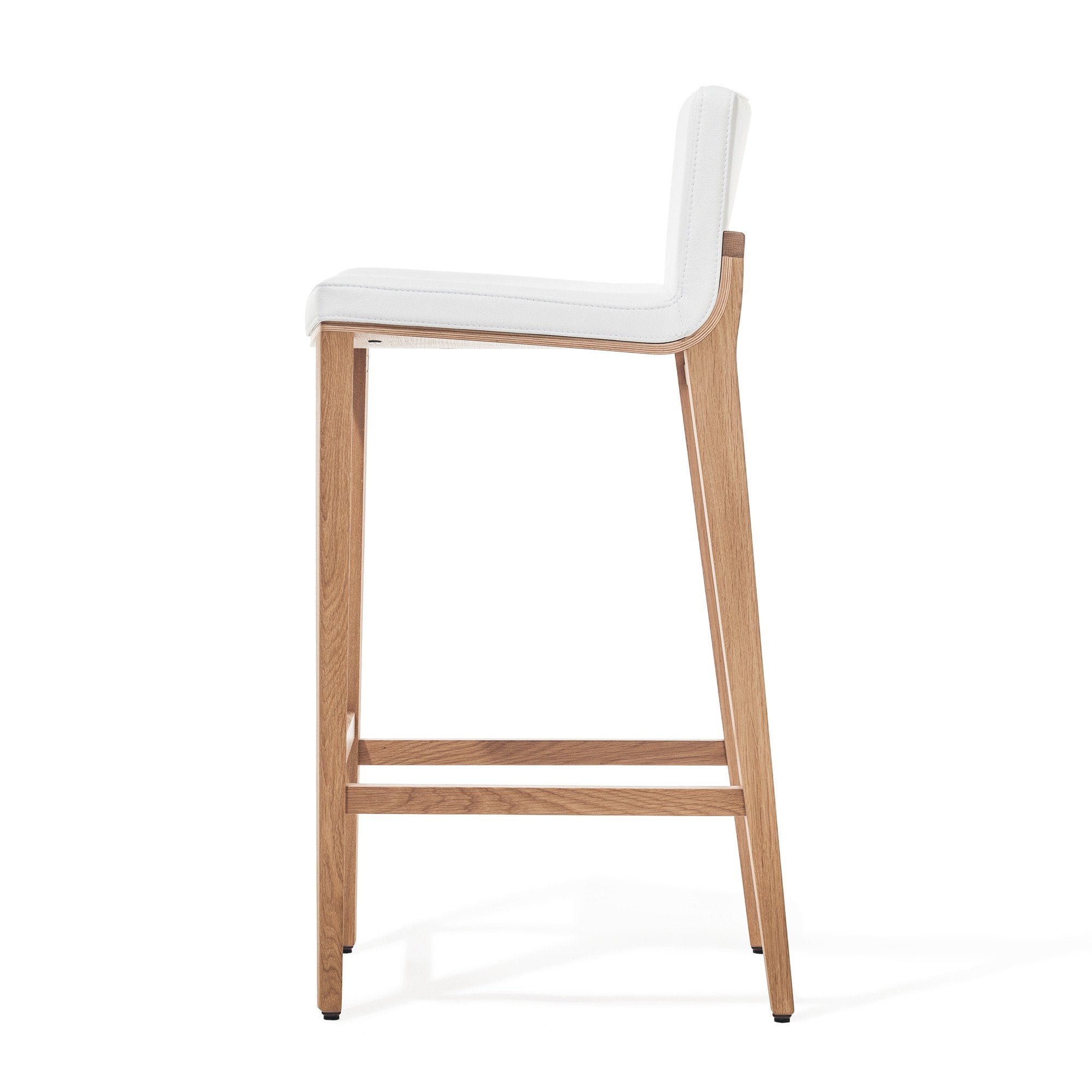 Side view of the Barstool Moritz by TON, featuring a white cushioned seat and backrest on a light wooden frame with two crossbars for stability. This ergonomic piece showcases sleek lines and contemporary design.