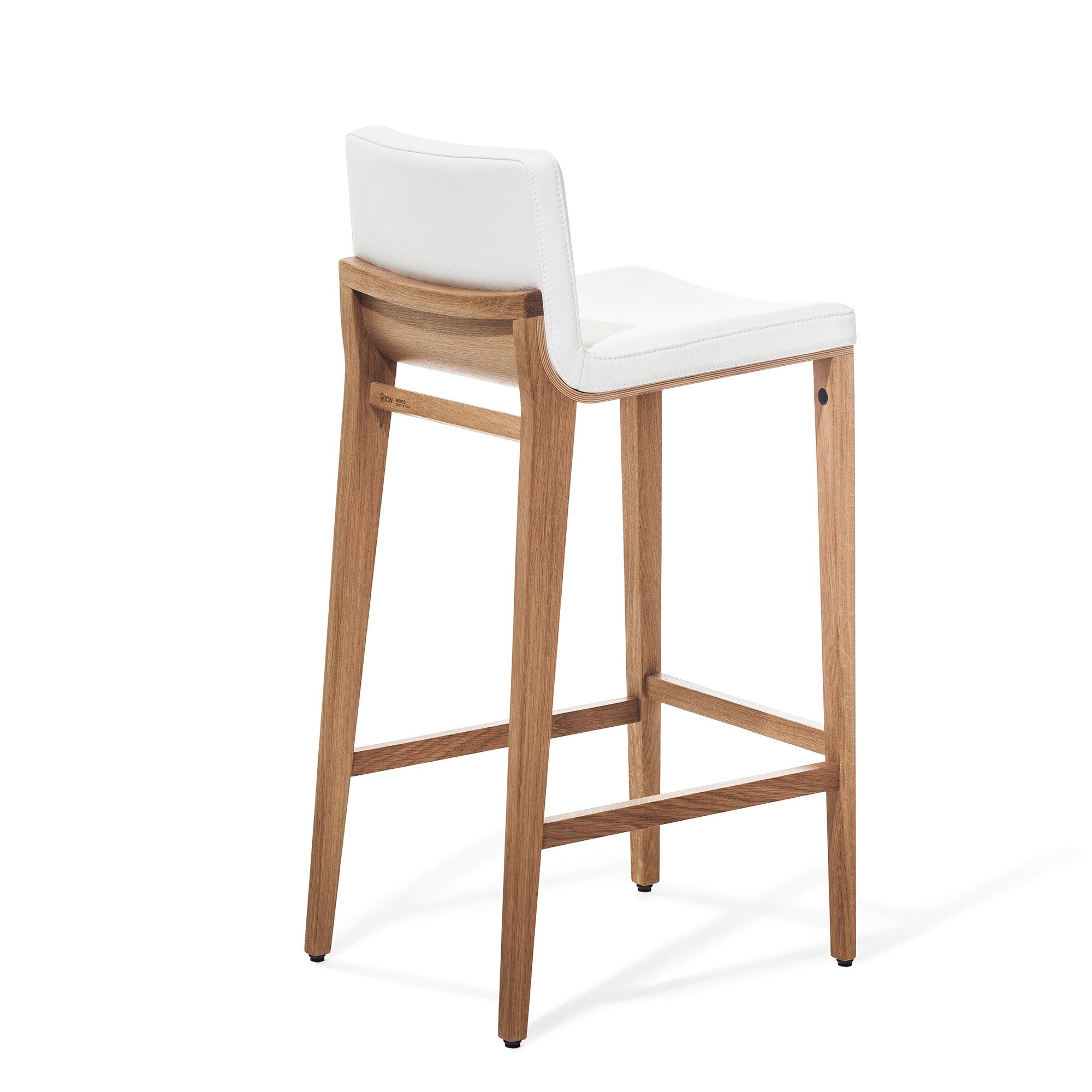The Barstool Moritz by TON boasts a wooden frame with a white cushioned seat and backrest, highlighting its sleek, modern design. It features four legs and an ergonomic footrest, seamlessly blending style and comfort.