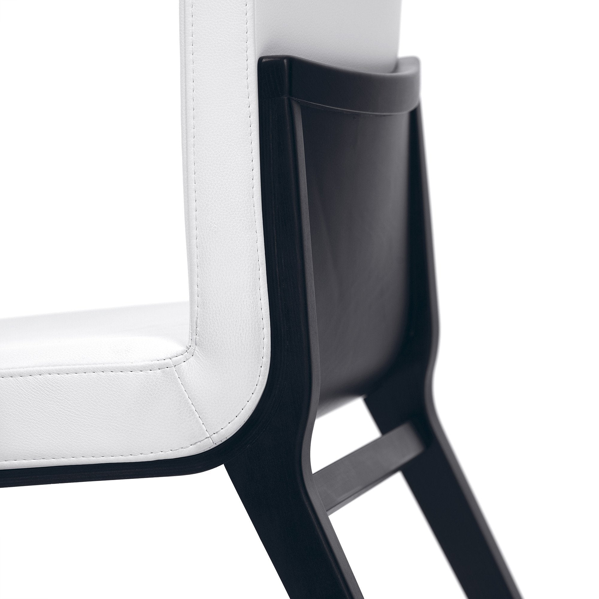 A close-up of the Chair Moritz by TON features a white cushioned seat and backrest in fine natural leather, paired with sleek black wooden legs and frame. Hand-smoothed wood highlights its clean lines, enhancing the chairs ergonomic design and bold color contrast.