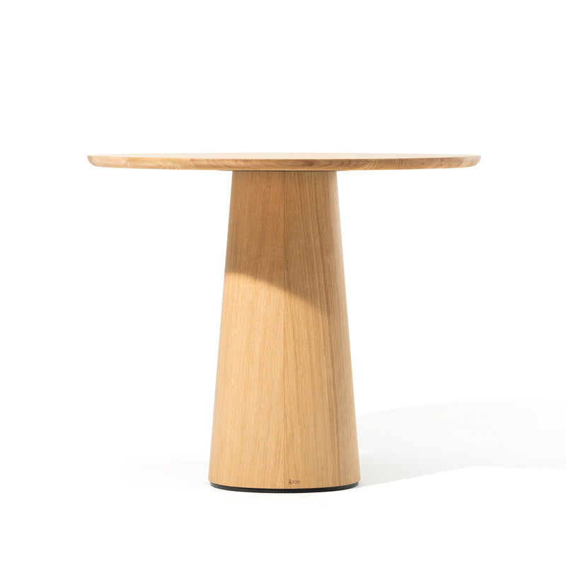 The P.O.V. Table 460 by TON is a minimalist round table with a light wood finish and a sleek conical pedestal base that embodies modern elegance. Its durable tabletop against a white background enhances its chic appeal.
