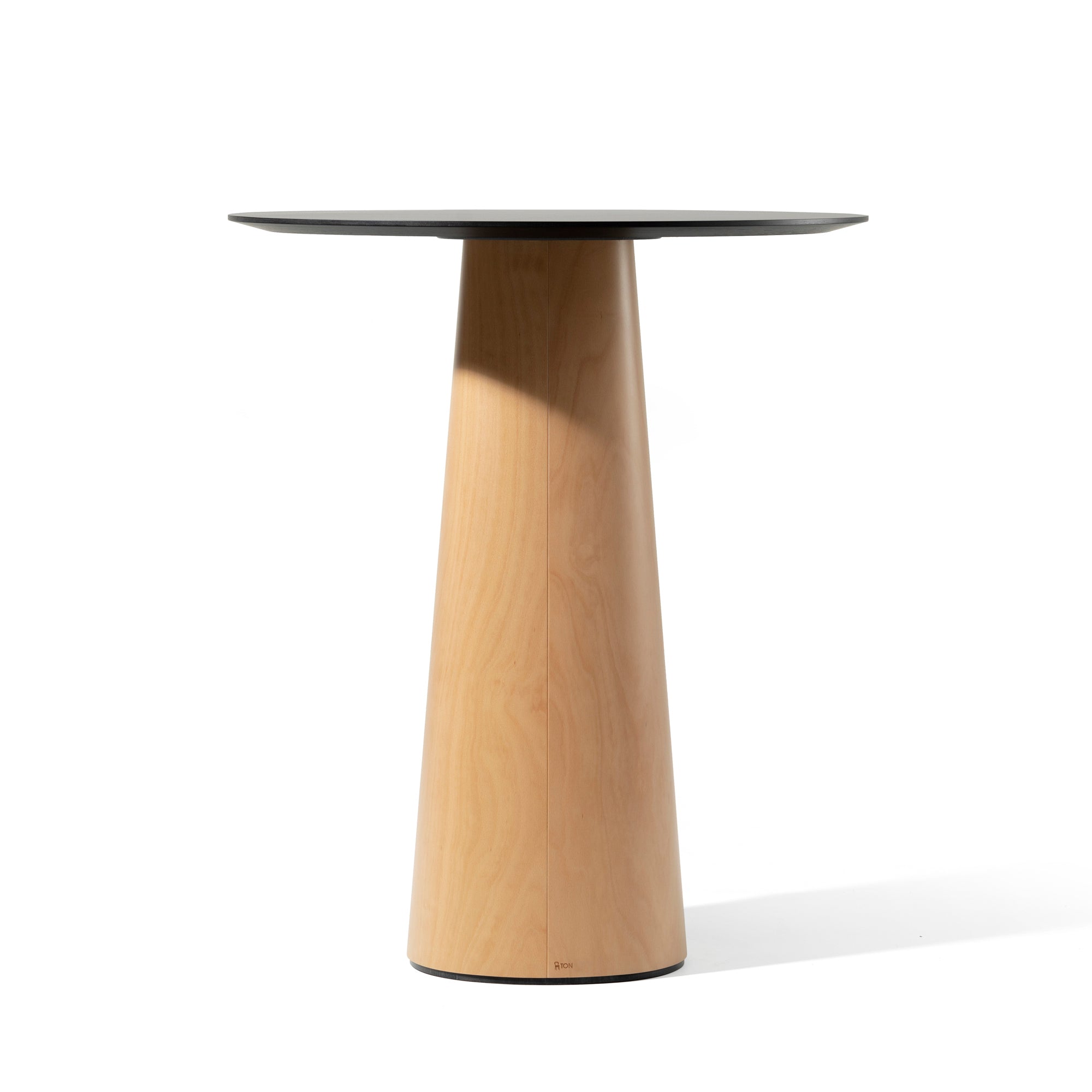 The P.O.V. Table 463 by TON showcases a sleek, black circular top with an organically shaped design and a conical wooden base. Its elegantly centered against a plain white background.