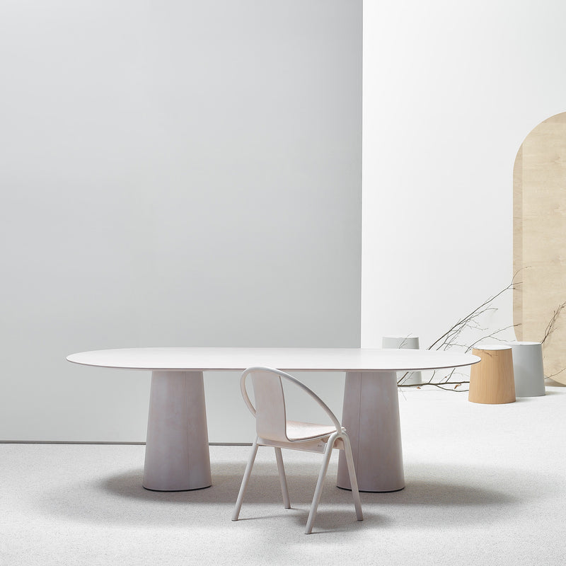 The minimalist room showcases a TON P.O.V. Table 464 with an organically shaped base and a matching chair. It features neutral tones, a light gray wall, and a wooden arch accent. The sparse decor and clean lines highlight simplicity and modern design.