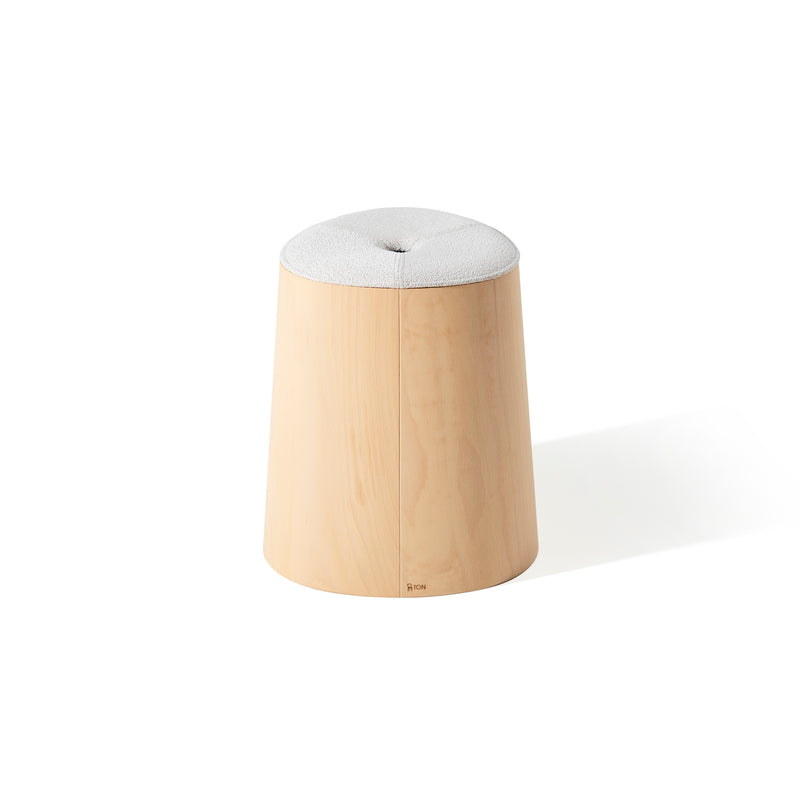 The P.O.V. Stool Upholstered by TON is a wooden stool with a cushioned, light-colored circular seat made from American walnut. Its minimalistic design includes a slightly tapered cylindrical base with smooth lines, elegantly showcased against a white background.