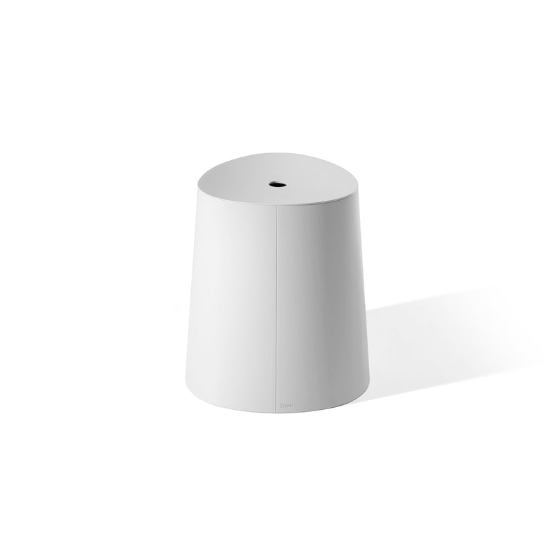 The TON P.O.V. Stool, a minimalist white cylinder, boasts a matte finish and a unique top hole, offering modern flair. Its stackable design makes it ideal for adaptable dining spaces.