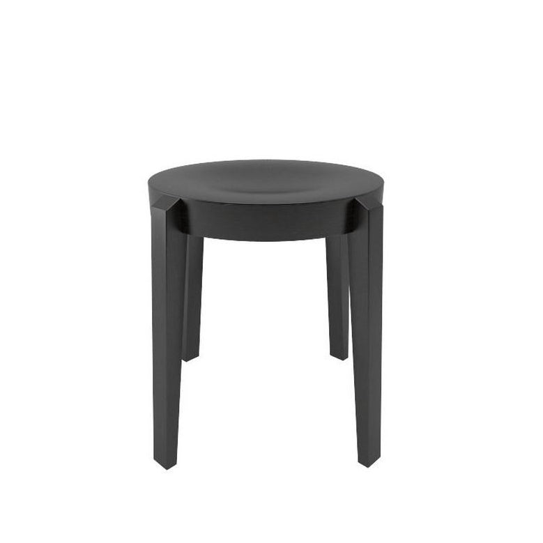 Introducing the Stool Punton by TON: a modern black stool featuring a round seat and four angular beech legs. Its sleek, minimalist design is ideal for contemporary interiors.