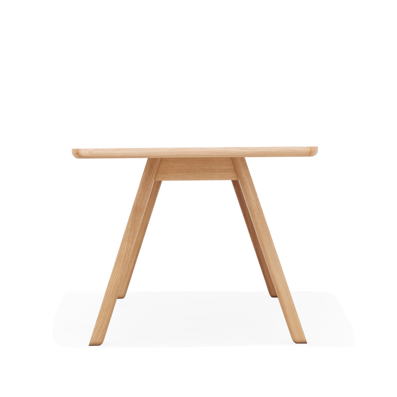 The Table Stelvio by TON is a minimalist design, featuring a rectangular solid wood top supported by two angled legs that form triangles on each side, all set against a plain white background.