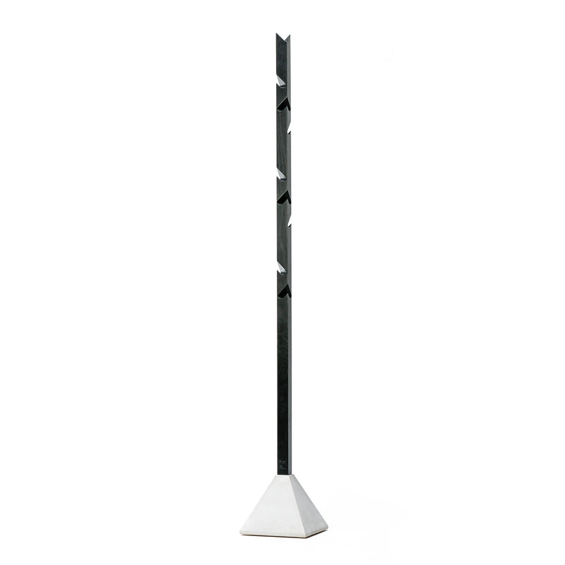 The Tee by TON is a modern, minimalist coat rack with an angular metal design that stands vertically on a sleek oak and concrete base, featuring evenly spaced hooks.