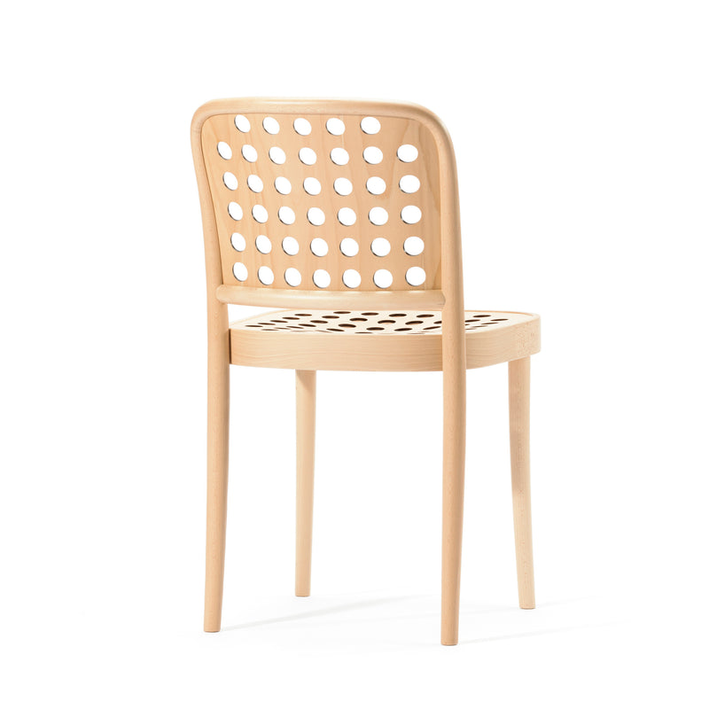 The Chair 822 by TON embodies Scandinavian minimalism, featuring a natural finish with a rounded backrest and circular cutouts on the seat. Made with manual wood-bending technology, it stands elegantly on four sleek legs.