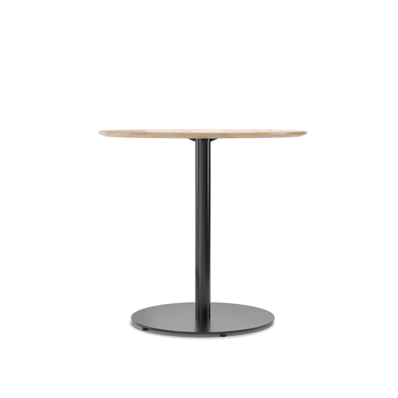 The Easy Bistro Table Round by TON is a round wooden table with a light finish and sleek black metal pedestal base, elegantly suited for bistro and bar height settings against a plain white background.